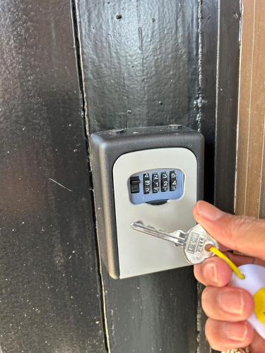 a person unlocking a door with a pair of keys at ゲストハウス 畔（hotori） in Nishimukai