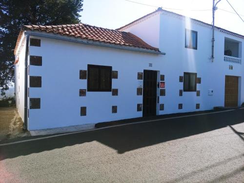 un edificio blanco con puertas y ventanas negras en LA CASA DE PÁ en Vega de San Mateo