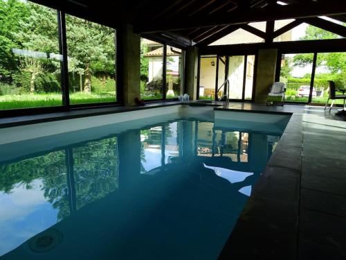 uma grande piscina numa casa com o reflexo na água em Chalet con piscina climatizada. 