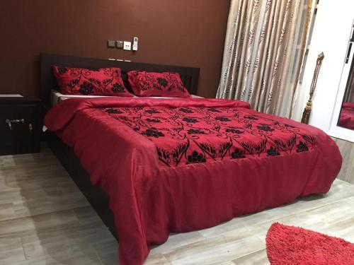 - une chambre dotée d'un lit rouge avec des draps et des oreillers rouges dans l'établissement La belle au bois dormant, à Abomey-Calavi