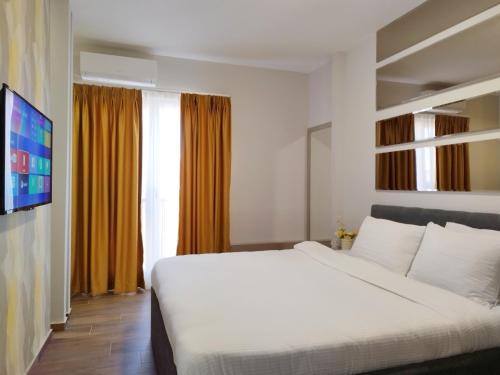 Schlafzimmer mit einem weißen Bett und einem Flachbild-TV in der Unterkunft Urban Vista Apartments in Ohrid