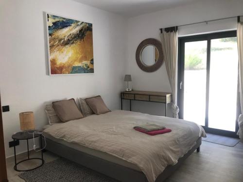 1 dormitorio con cama y espejo en la pared en Villa Coco , un lieu convivial où se ressourcer., en Kalafatiónes
