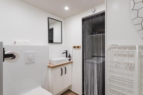 La salle de bains est pourvue d'un lavabo et d'une douche. dans l'établissement Le Petit Chalet - Maison 2 chambres avec terrasse, à Rennes