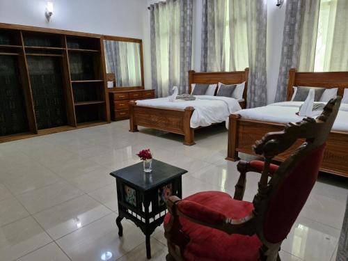 a bedroom with two beds and a chair and a table at 64 ZENJ HOUSE Luxury Airport B&B in Mbweni