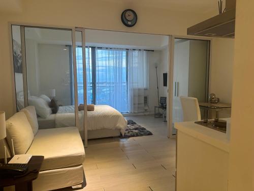 マニラにあるC&J Staycation by Azureのリビングルーム(ベッド1台、ソファ、時計付)
