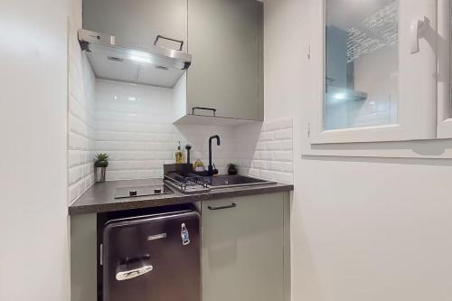 une petite cuisine avec un évier et un réfrigérateur dans l'établissement Studio 2 Joli studio neuf veranda d ete bords de Marne 5 km paris, à Champigny-sur-Marne