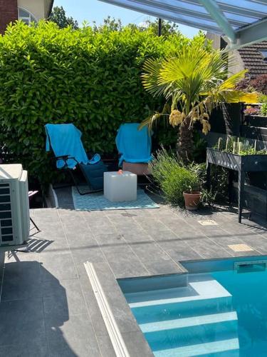 une terrasse avec 2 chaises bleues et une piscine dans l'établissement Studio 2 Joli studio neuf veranda d ete bords de Marne 5 km paris, à Champigny-sur-Marne
