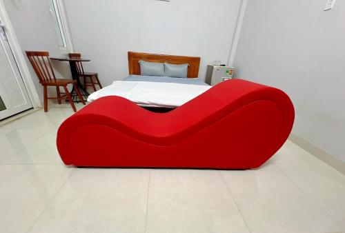 a red couch sitting in front of a bed at An Phát Hotel in Thôn Mỹ Phước