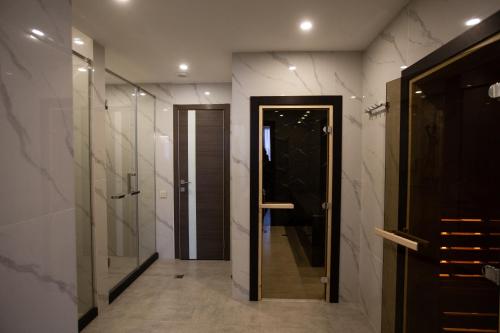 baño con ducha a ras de suelo y puerta de cristal en Arman Dala Resort en Kaskelen
