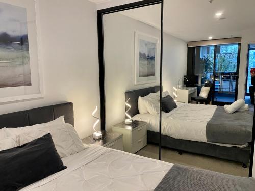 - une chambre avec 2 lits et un miroir dans l'établissement Midnight Luxe 1 BR Executive Apartment L1 in the heart of Braddon Pool Sauna Secure Parking Wine WiFi, à Canberra