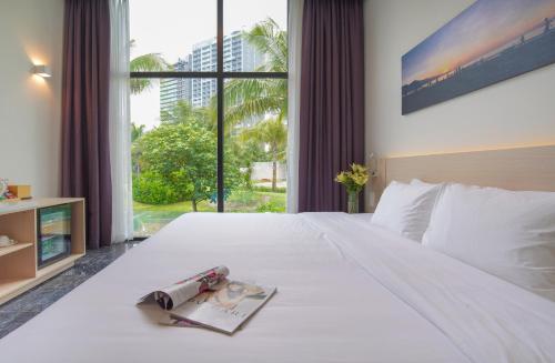 Un dormitorio con una cama blanca con una revista. en Temple Da Nang Resort, en Da Nang