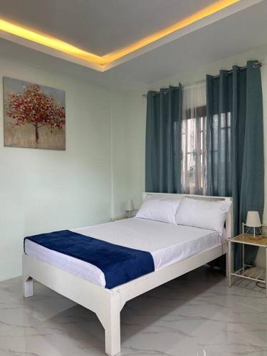 a bedroom with a white bed with a blue blanket at Faith Street Airbnb in Plaridel