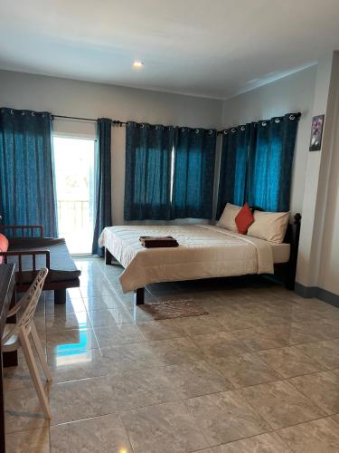 a bedroom with a large bed and blue curtains at Nare Guest House in Ko Lanta