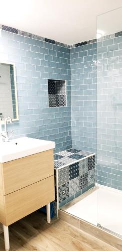 uma casa de banho com um lavatório e uma banheira com azulejos azuis em Gîte Timéo Mont Saint-Michel em Pontorson
