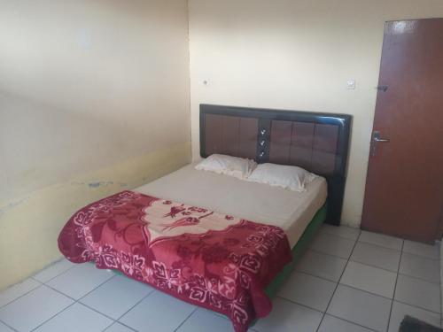 una camera da letto con un letto con una coperta rossa sopra di Gundaling 1 Guest House a Berastagi