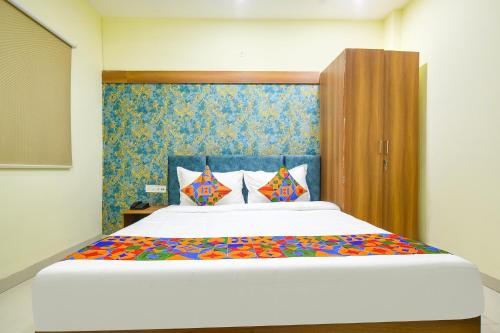 インドールにあるFabHotel Grand Girirajのベッドルーム(カラフルなシーツを使用した大きな白いベッド付)
