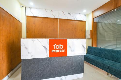 a lobby with a blue couch and a red sign at FabHotel Grand Giriraj in Indore