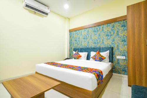 a bedroom with a large white bed with a blue wall at FabHotel Grand Giriraj in Indore