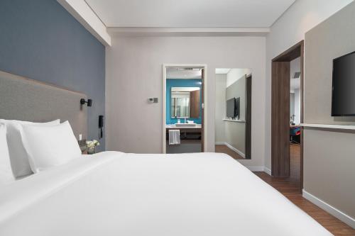 a bedroom with a large white bed and a bathroom at Holiday Inn Express Xiamen Lushan -Shopping Center by IHG in Xiamen