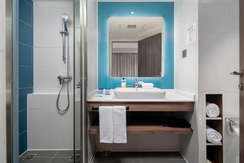 a bathroom with a sink and a mirror and a shower at Holiday Inn Express Xiamen Lushan -Shopping Center by IHG in Xiamen