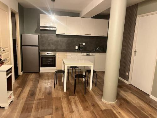 a kitchen with a white table and black appliances at Le 24 carat appartement 3 pièces neuf in Beaurepaire