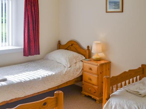 a bedroom with two beds and a lamp on a dresser at Sandy Bay in Portmahomack