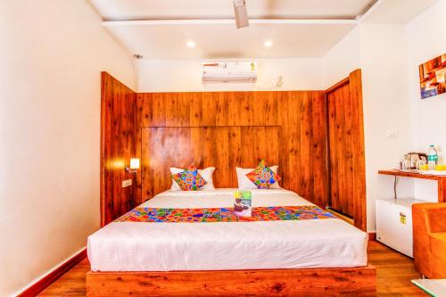 a bedroom with a large bed with a wooden headboard at FabHotel V Suites Bangalore East Railway Station in Bangalore