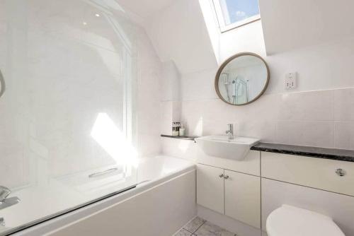 a white bathroom with a sink and a mirror at Abbey Villa - Stylish House - Central with Parking in St Andrews