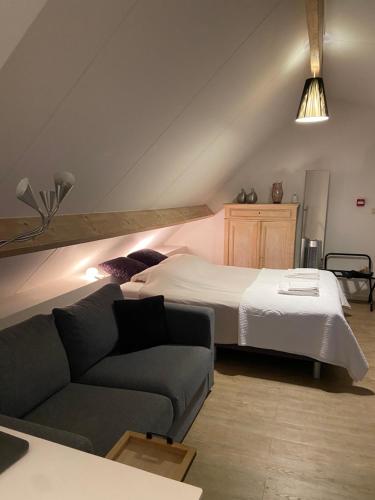 um quarto com uma cama e um sofá em Begijnhofstudio's em Tongeren