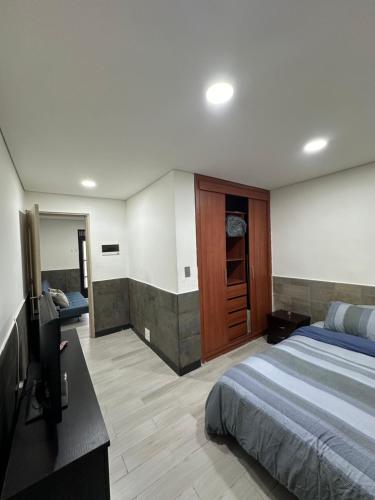 a bedroom with a bed and a flat screen tv at APARTA/ESTUDIO INDEPENDIENTE GALERIAS-CHAPINERO in Bogotá