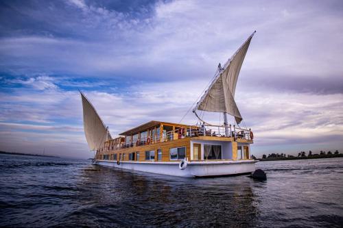 un barco con dos grandes velas en el agua en Dahabiya Akhnaton Every Monday from Esna to Aswan for 4 Nights en Luxor