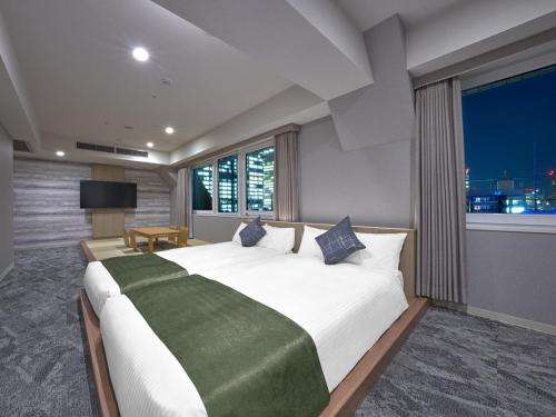 um quarto com uma cama grande e uma janela grande em Hotel Villa Fontaine Tokyo-Otemachi em Tóquio