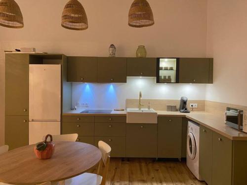 a kitchen with green cabinets and a table and a sink at Entre terre & mer in Bénesse-Maremne