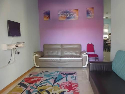 uma sala de estar com um sofá e uma parede rosa em Homestay Ainul em Pendang