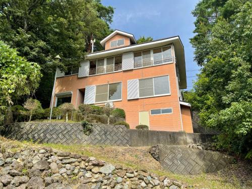a large orange house on top of a stone wall at New open【Mermaid annex】最大13名可！壮大な富士山の景色を楽しむ、高級貸別荘！ in Oishi