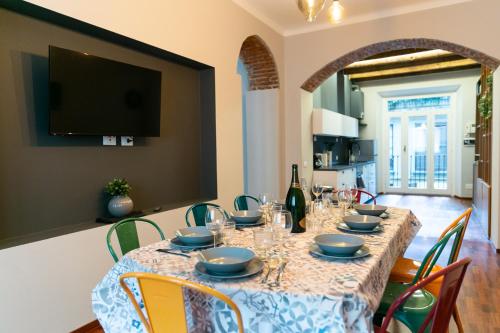 sweet house deluxe في ميلانو: غرفة طعام مع طاولة مع كراسي وتلفزيون