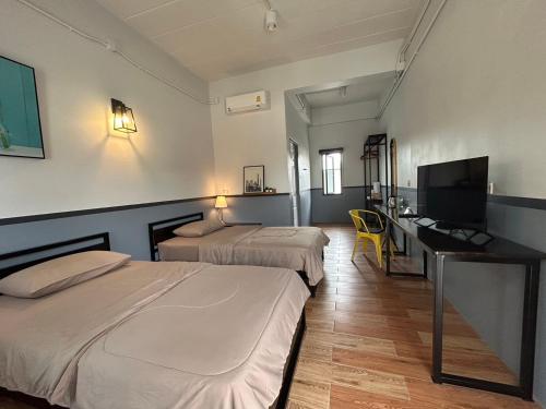 una camera d'albergo con 2 letti, una scrivania e una TV di บ้านสุขซอย5 a Kanchanaburi
