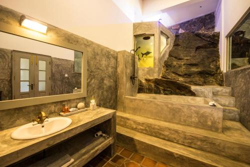 a bathroom with a sink and a rock wall at The Horizon Hill Top Villa in Unawatuna