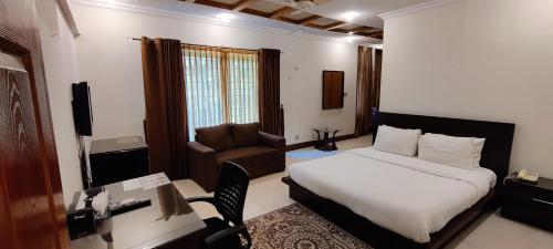 a bedroom with a bed and a desk and a chair at Capri Executive in Islamabad