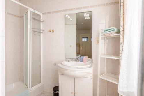 a white bathroom with a sink and a shower at Cosy apartment 150m from the beach in Blankenberge