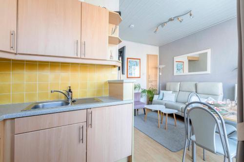a kitchen with a sink and a living room at Cosy apartment 150m from the beach in Blankenberge