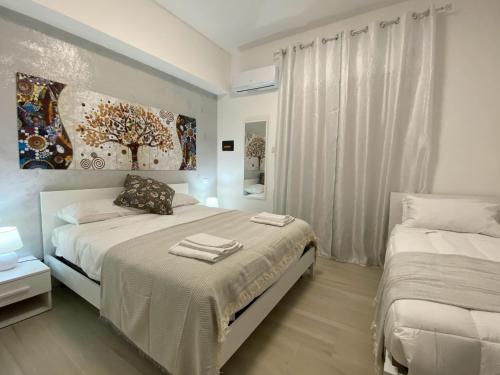 a white bedroom with two beds and a window at Central Apartments in Crotone