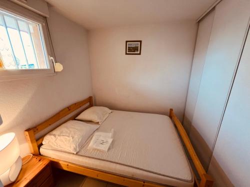 - un petit lit dans une petite chambre avec fenêtre dans l'établissement AZUREVA II Joli 2 pièces cabine piscine Richelieu Cap d'Agde, au Cap d'Agde