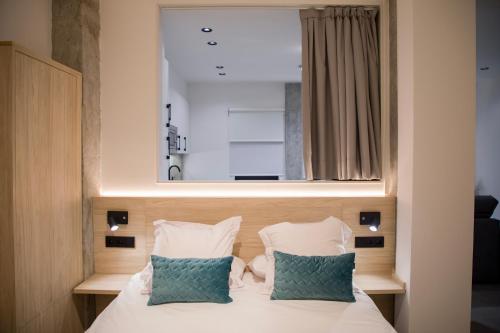 Una cama con dos almohadas y un espejo encima. en Ponteloft - Xeitoso, en Pontevedra