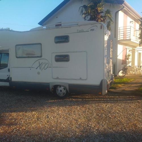 un remolque blanco estacionado frente a una casa en Mimoza Camper en Bibione