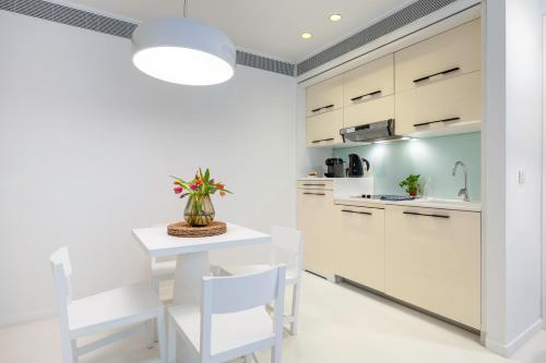 a kitchen with white cabinets and a white table and chairs at B-aparthotel Regent in Brussels