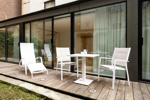 a patio with white chairs and a table at B-aparthotel Regent in Brussels
