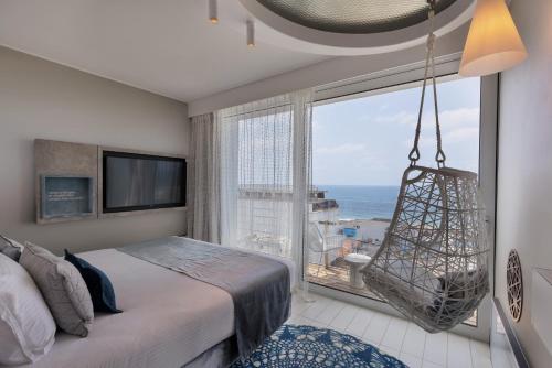 a bedroom with a bed and a large window at Port Tower by Isrotel Design in Tel Aviv