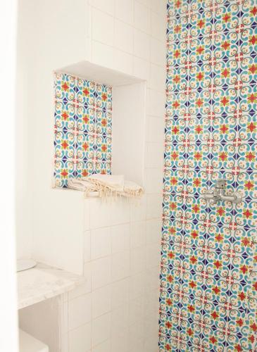 a bathroom with a tiled shower with a patterned shower curtain at Dar Yessine Boutique Hôtel in Sousse