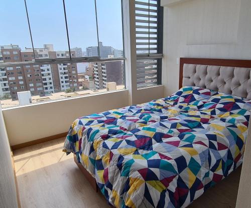a bedroom with a bed and a large window at Acogedor departamento con vista al mar in Lima